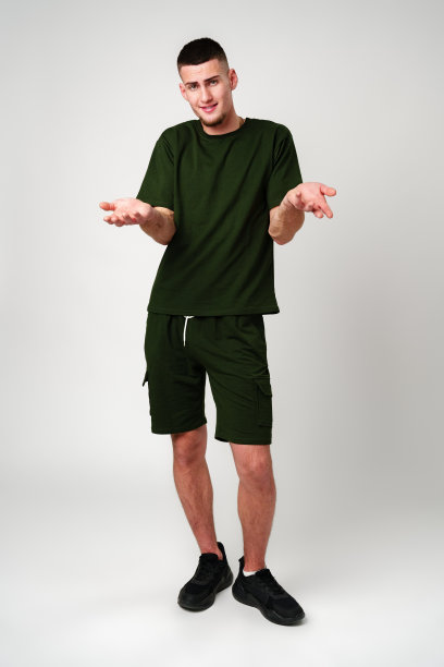 一个穿着绿色t恤的年轻人在白色背景前用双手打手势图片下载