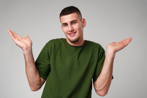 一个穿着绿色t恤的年轻人在白色背景前用双手打手势图片下载