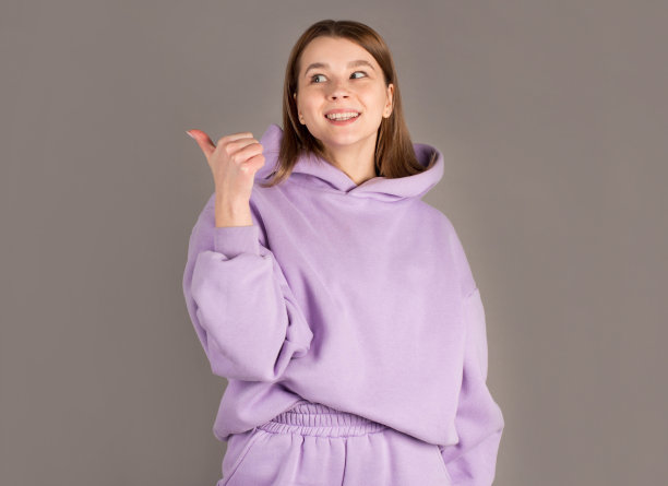 美女微笑着黑发女人指着远处，看着灰色背景下的相机图片下载