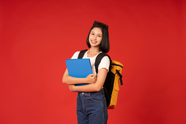 这张亚洲女学生的照片以鲜红色为背景，突出了她对教育的承诺，展示了她泰然自若的风度和对学习的投入。图片下载