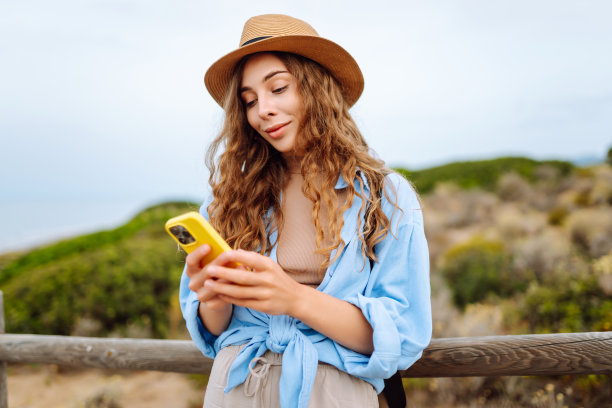 快乐的女人——带着手机欣赏美景的游客。图片下载