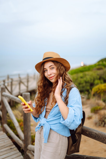 快乐的女人——带着手机欣赏美景的游客。图片下载