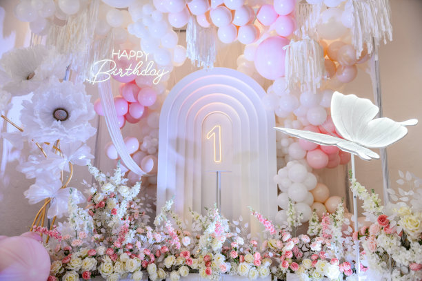 背景照片墙上1岁女孩的生日派对。粉红色的拱门装饰，白色的气球，生日快乐的文字，鲜花，蝴蝶纸装饰。儿童照相区。特写镜头。图片下载