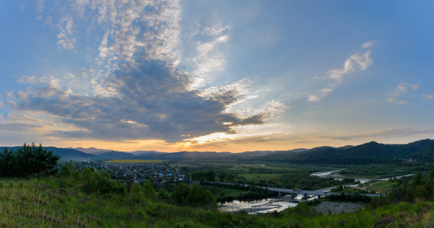 美丽的风景和蓝天。春天的夕阳在村庄上空。有田野和山脉的乡村景观。照片的背景是村庄的景色和阳光。图片下载