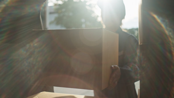 快递员正在往她的车里装纸箱。图片下载