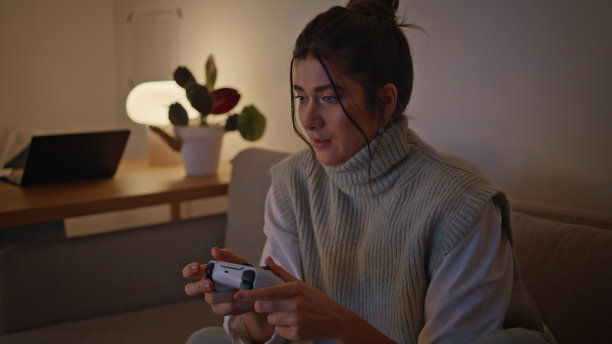 专注玩家游戏控制器在晚上的家庭特写。拿着操纵杆的女人图片下载