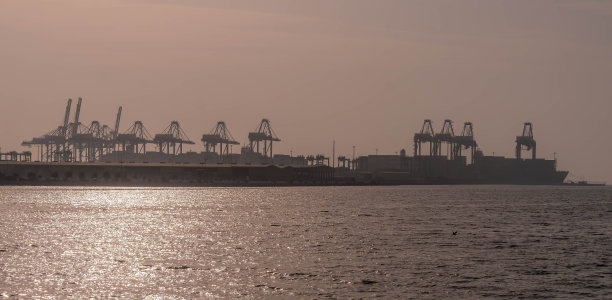 沙特阿拉伯吉达伊斯兰港口的照片，红海沿岸有起重机、货船和码头图片下载