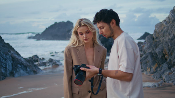 摄影师在岸边讨论模特照片的特写。拍摄团队工作图片下载