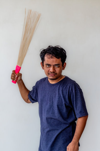 一名成年男子正愤怒地准备用孤立在白色背景上的扫帚扫射。对于与愤怒、沮丧或冲突有关的主题，这张照片非常适合描绘情绪紧张。图片下载