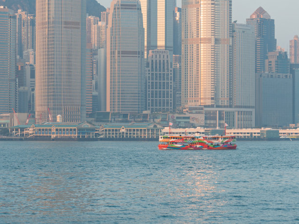上午从维多利亚港眺望香港市景，船只在蓝色的海面上航行，背景是现代建筑。图片下载