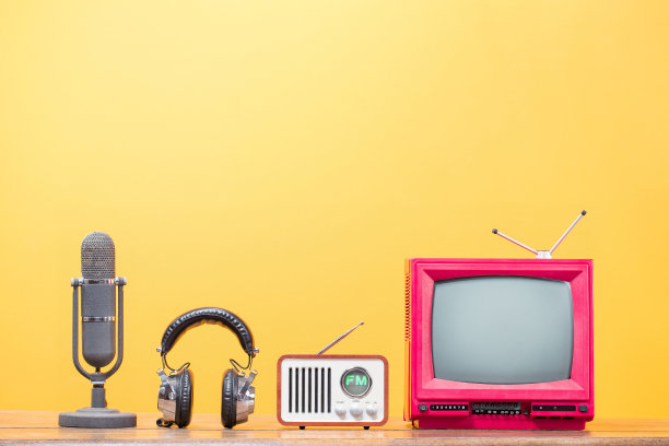 复古电视，调频收音机，耳机和旧麦克风前黄色背景。复古滤镜照片图片下载