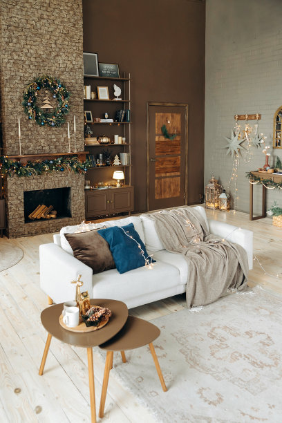 沙发与枕头和格纹在圣诞室内舒适的客厅与壁炉和书柜的书籍和装饰。壁炉上的圣诞花环。圣诞装饰房图片下载