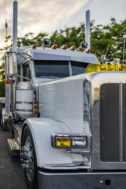 闪亮的白色经典引擎盖大钻机半卡车与雾灯和喇叭的车顶站在卡车停车停车场在晚上的时间图片下载