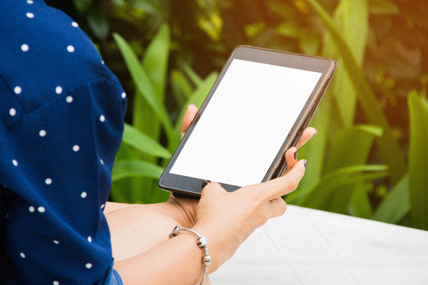 裁剪图片的女人使用数字平板电脑，而坐在桌子上图片下载