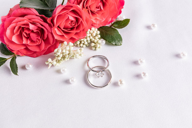 精致的婚礼安排与两个婚礼铂金戒指白色缎面背景与珍珠珠和鲜花。明信片。的邀请。封面图片下载