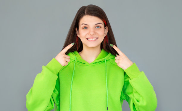 美丽的女人指着牙齿和微笑的照片孤立在灰色的背景图片下载