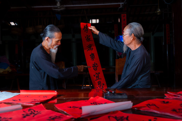老书生在中国农历新年写春联。春联是中国春节期间的一项流行传统。照片中的文字意味着新年快乐，平平安安。图片下载