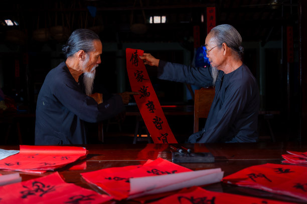 老书生在中国农历新年写春联。春联是中国春节期间的一项流行传统。照片中的文字意味着新年快乐，平平安安。图片下载