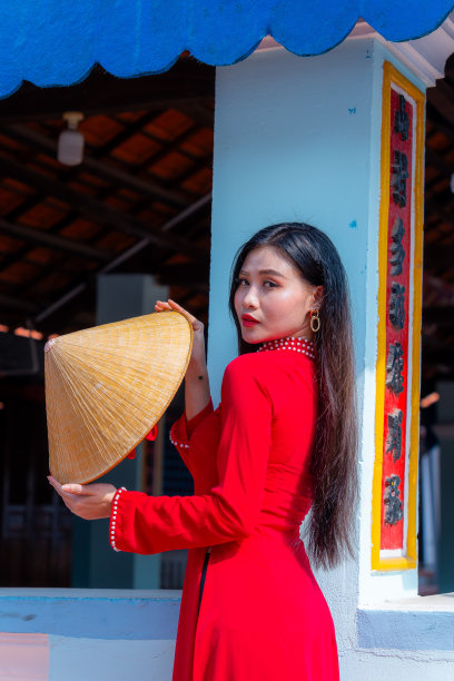 越南女孩穿着敖黛服装站在越南传统的房子里。照片中的文字代表着对家人、幸福、成功、健康的美好祝愿。春节和新年。图片下载