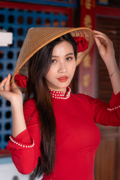 越南女孩穿着敖黛服装站在越南传统的房子里。照片中的文字代表着对家人、幸福、成功、健康的美好祝愿。春节和新年。图片下载