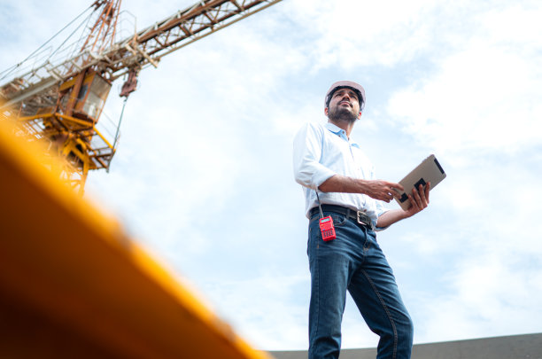 工程师在建筑工地用塔式起重机吊起和移动物体的肖像图片下载