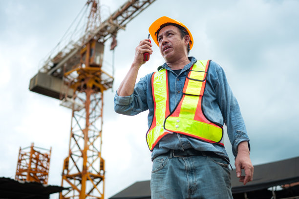 起重机工人肖像使用对讲机与塔式起重机操作员通信，以提升和移动建筑工地上的物体图片下载