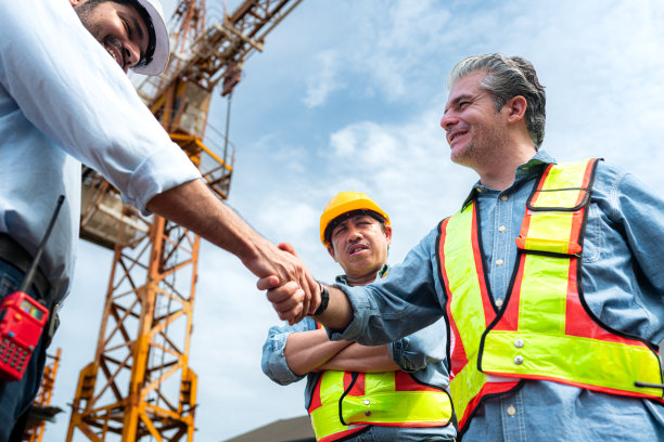 图为，工地上的工人们正在讨论施工进度，背景是塔吊图片下载