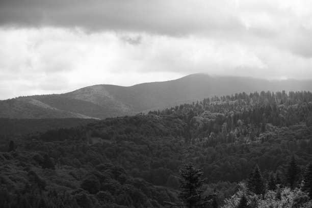 这是一张令人不安的黑白照片，比什恰迪山峰上方有云，太阳穿过云层图片下载