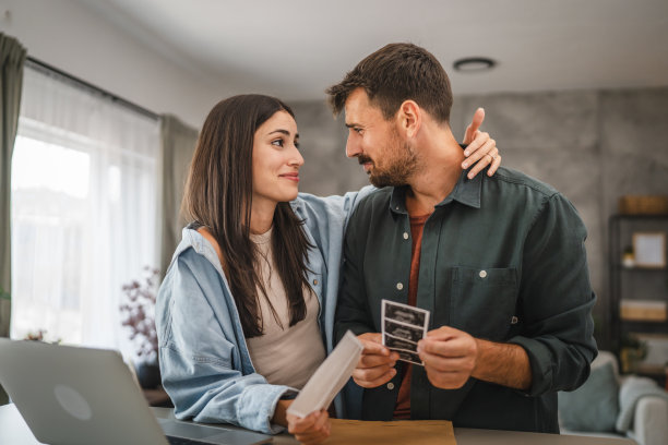 一对幸福的热恋夫妇抱着他们第一个孩子的超声波照片图片下载