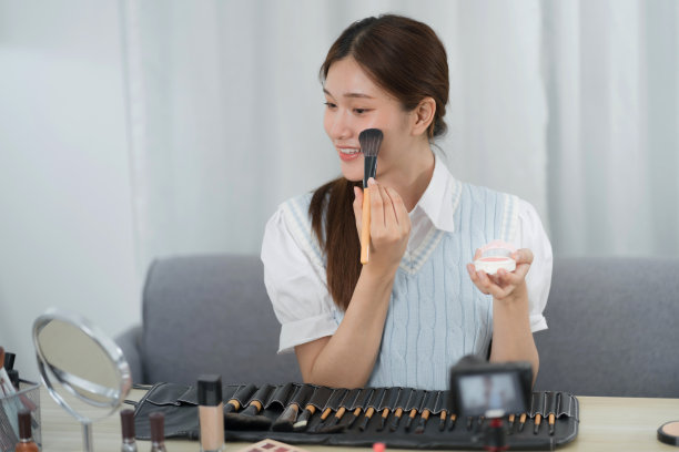 美博主。快乐的亚洲视频博主正在展示化妆品productsÂ，为她的美容博客提供建议图片下载