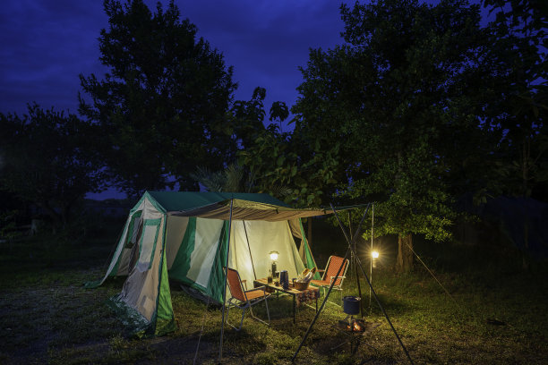 夜晚的露营帐篷，复古的小屋帐篷，古董油灯，复古的椅子，森林中的森林露营区，木桌上有户外咖啡制作设施的一组露营帐篷图片下载