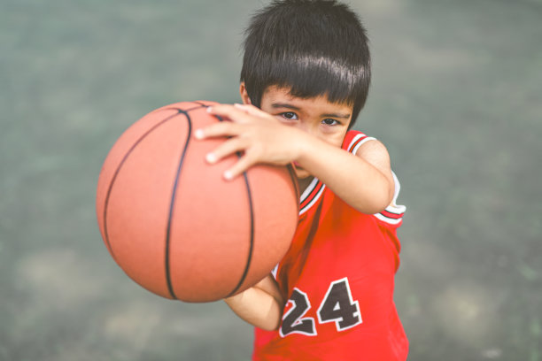 一个男孩在公园里打篮球的照片图片下载
