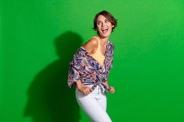 时髦少女的照片与鲍勃发型在印花衬衫上打结看着销售空白空间孤立的绿色背景图片下载
