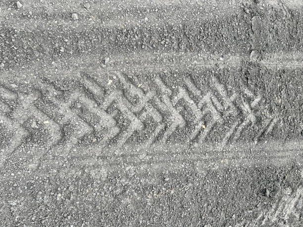 沙滩上的轮胎印和一把红色雨伞的照片。图片下载
