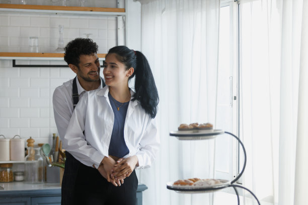 男人和女人在厨房，一对厨师在家里的厨房做饭。男女在糖果店拥抱。一对面包店老板。图片下载