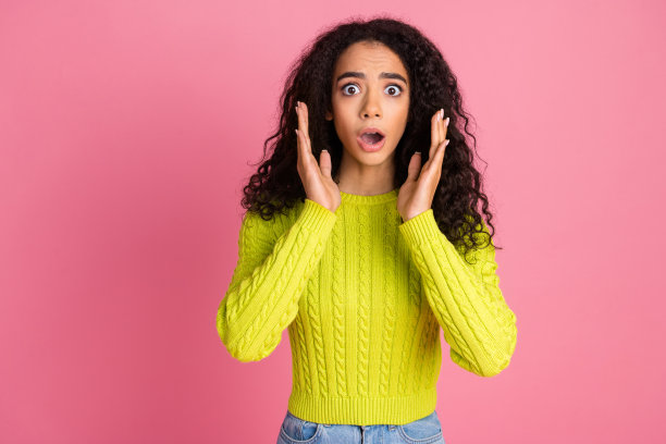 年轻的拉丁女孩的照片肖像波浪深褐色的卷发穿着绿色的毛衣害怕感到内疚孤立在粉红色的背景图片下载