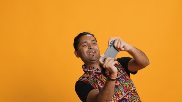 穿着传统服装的快乐男子正在玩手机上的电子游戏图片下载