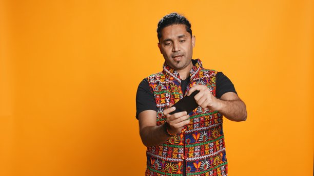 穿着传统服装的快乐男子正在玩手机上的电子游戏图片下载