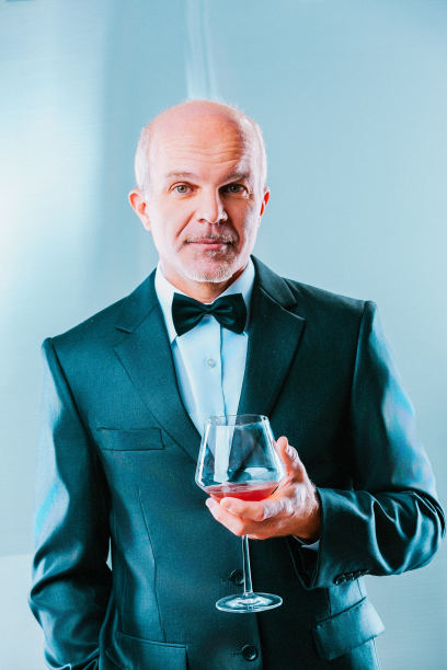 高级商人穿着西装，打着领结，端着一杯红酒图片下载