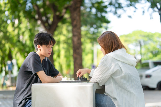 母亲带着儿子下棋，亚洲家庭在公园里下棋图片下载