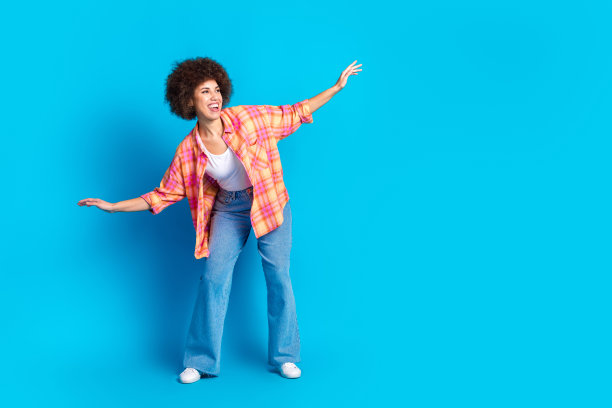 迷人的年轻女子冲浪保持平衡的全尺寸照片穿着时尚的格子衣服孤立的蓝色背景图片下载