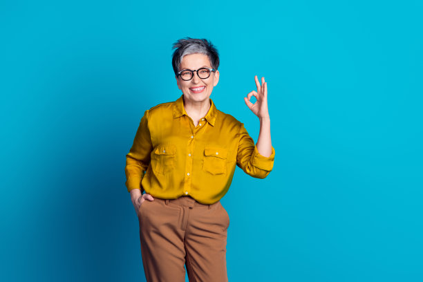 照片的迷人的积极的女人穿着衬衫眼镜显示ok标志空的空间孤立的蓝色背景图片下载