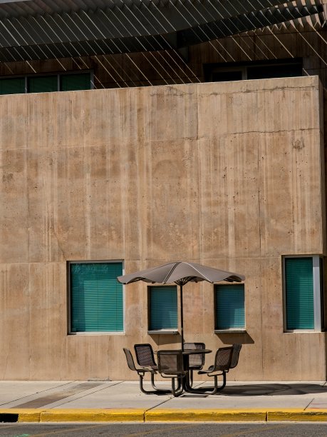 人行道上的野餐桌和雨伞，靠着土色的墙图片下载