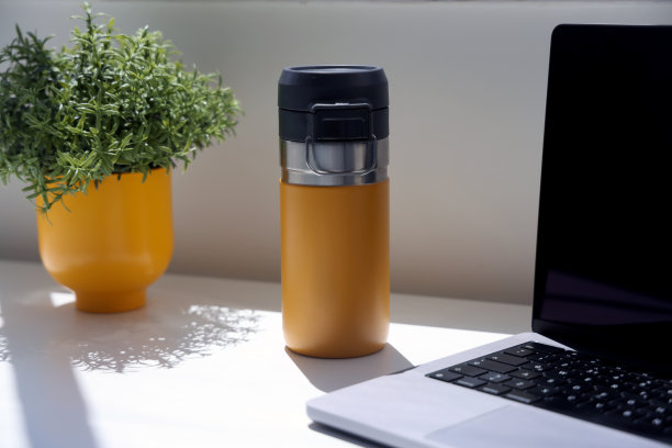 桌子上的咖啡杯和笔记本电脑在自然阳光下拍摄的照片图片下载