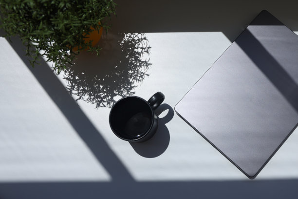 桌子上的咖啡杯和笔记本电脑在自然阳光下拍摄的照片图片下载
