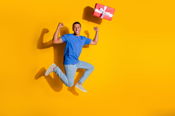 漂亮的年轻男性跑步的全尺寸照片赢得了礼物穿时髦的蓝色衣服孤立的黄色背景图片下载