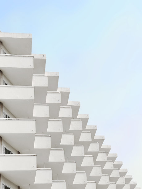 极简主义的度假酒店建筑的照片，重复图案的窗户和建筑元素和蓝天的背景图片下载