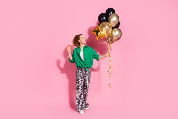 全身照片迷人的积极的女人穿绿色衬衫挥舞手臂上升气球花束空的空间孤立的粉红色背景图片下载
