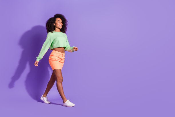 年轻的美国女孩的照片，波浪发型，穿着迷你裙和上衣，在紫色的背景上摆出孤立的模特图片下载