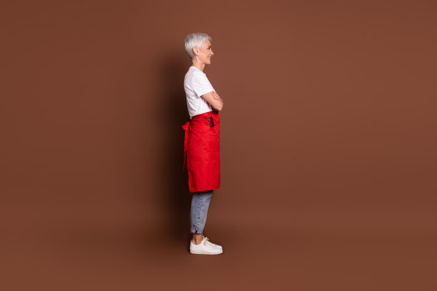 漂亮的资深女理发师美发店的全尺寸照片交叉双手轮廓穿制服孤立的棕色背景图片下载